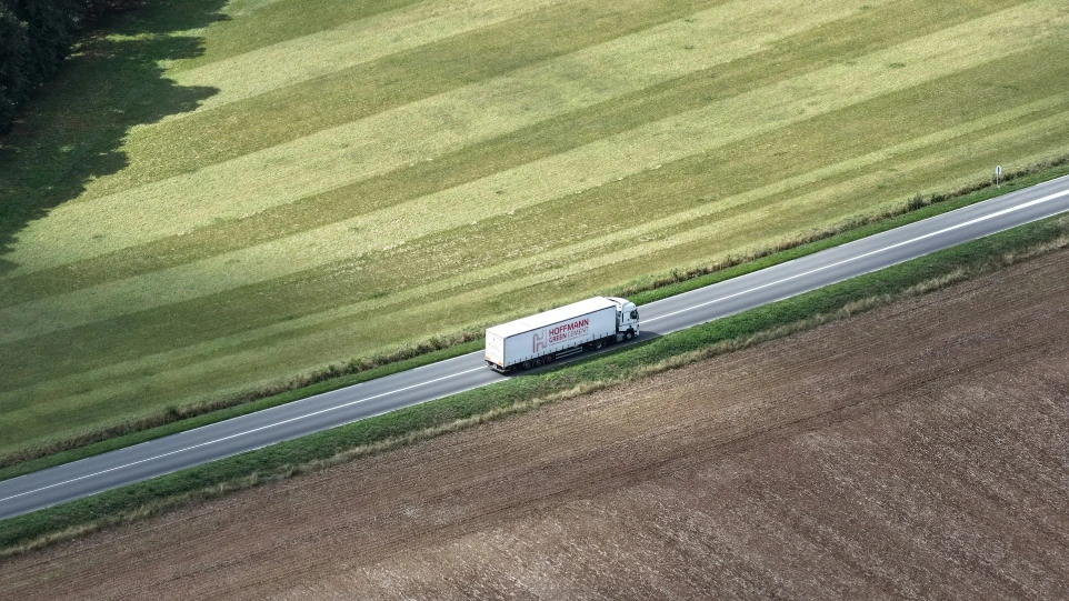 White truck driving on a road through fields