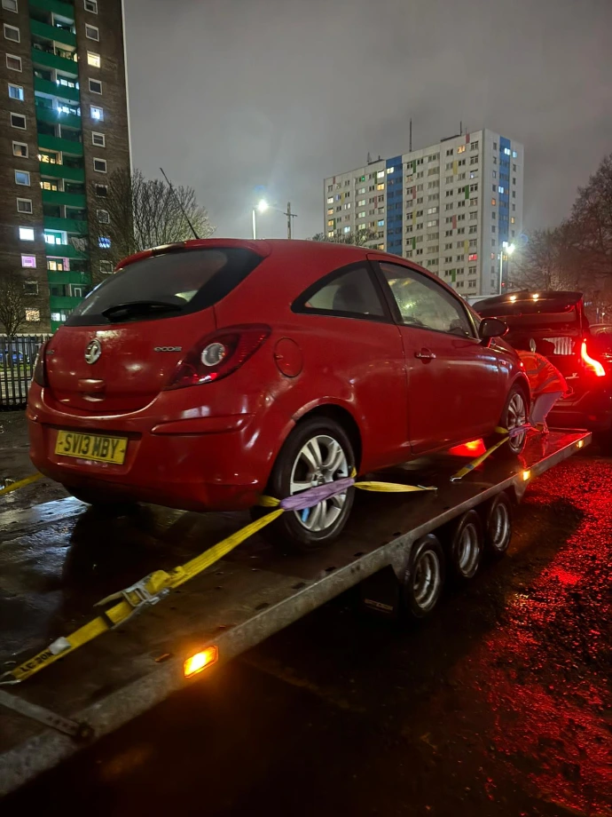 Red car being towed at night